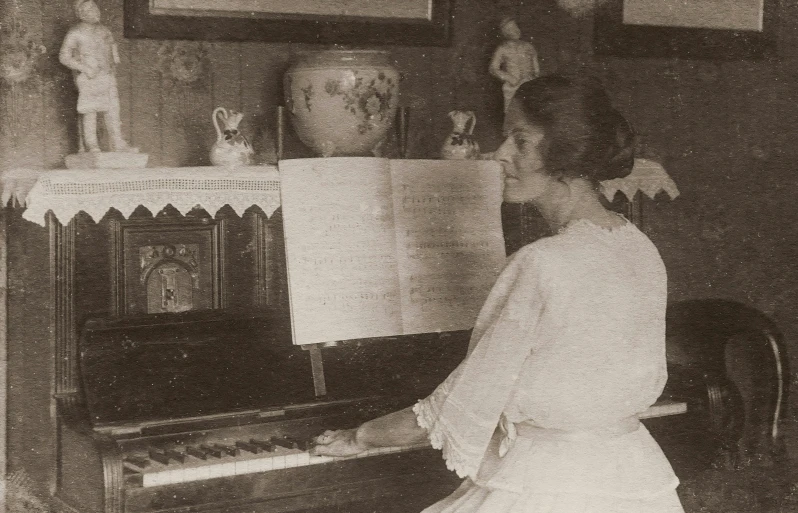 a black and white photo of a woman playing a piano, by Gertrude Greene, annie swynnerton, old color photograph, promo image