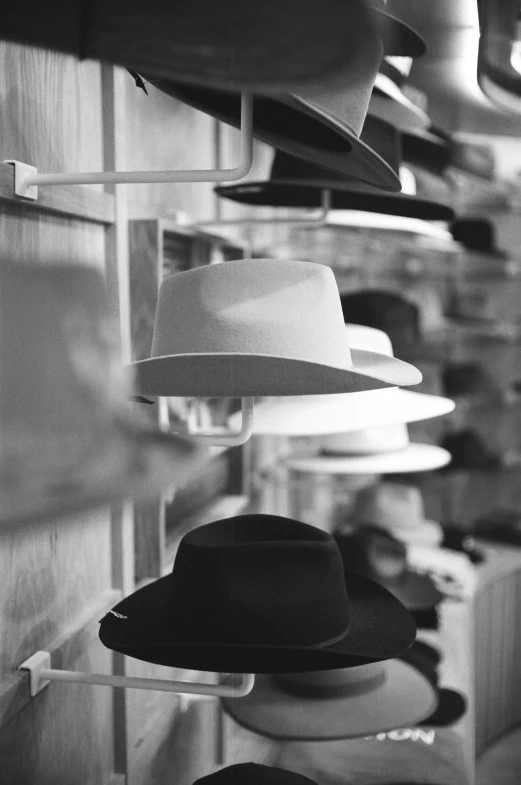 a black and white photo of hats hanging on a wall, profile image, digital image, ralph goings, store