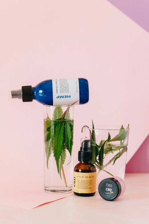 a bottle of liquid sitting on top of a table next to a glass of water, a still life, by Julia Pishtar, unsplash, with green cannabis leaves, pink and blue and green mist, skincare, 3 heads