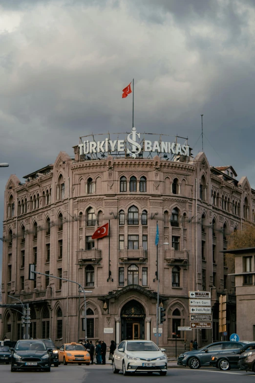 a group of cars driving down a street next to a tall building, inspired by Osman Hamdi Bey, pexels contest winner, art nouveau, set inside of the bank, turkey, square, exterior view