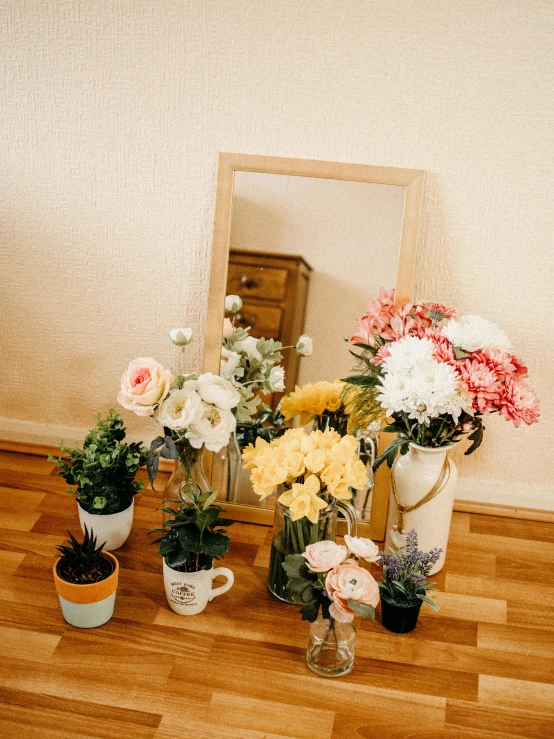 a mirror sitting on top of a wooden floor next to a bunch of flowers, low quality photo, pots with plants, detailed product image, pastel'