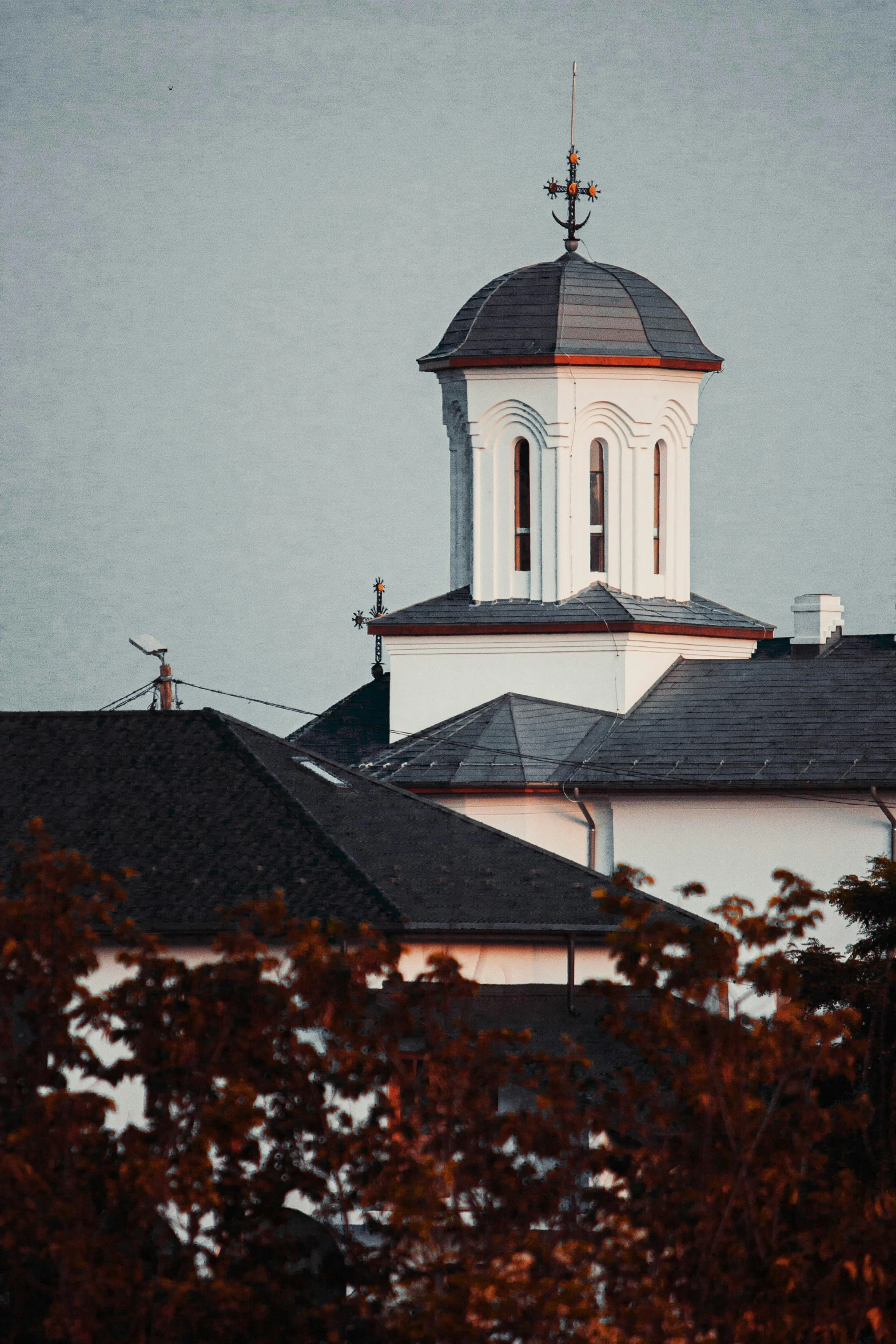 a clock tower on top of a white building, a colorized photo, by Attila Meszlenyi, unsplash, vancouver school, orthodox christianity, roof with vegetation, late summer evening, during autumn