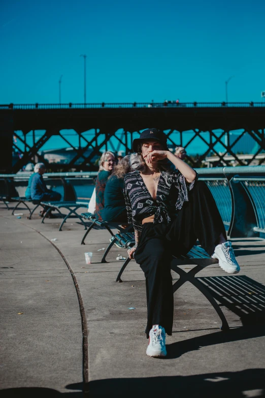 a woman sitting on a bench next to a body of water, woman in streetwear, digital photo, having a snack, group photo