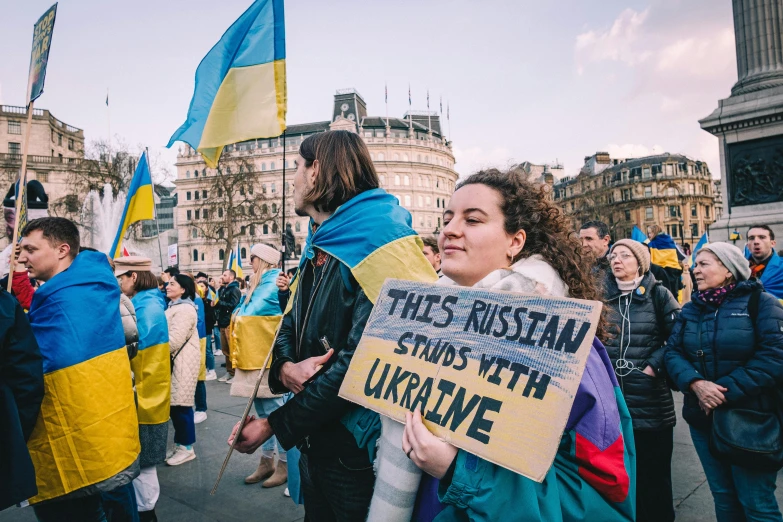 a group of people walking down a street holding signs, by Julia Pishtar, ukrainian flag on the left side, blue and yellow gradient, canva, square