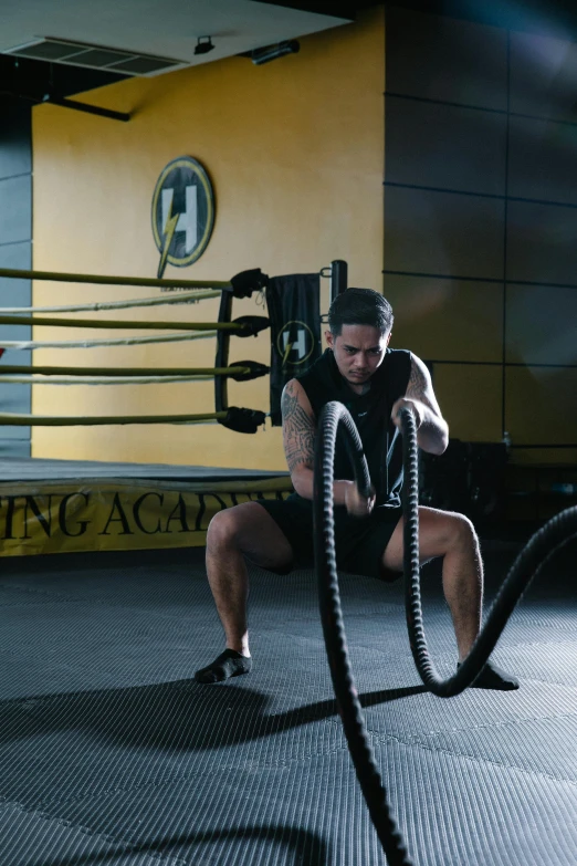 a man with a battle ropes in a gym, a portrait, by Nina Hamnett, pexels contest winner, hurufiyya, black and yellow scheme, ring lighting, lachlan bailey, profile image