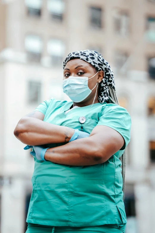 a woman in scrubs stands with her arms crossed, by Meredith Dillman, trending on pexels, happening, african canadian, scare, wearing gloves, multiple layers