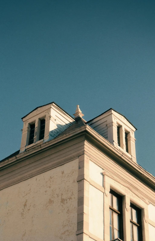 a clock that is on the side of a building, slanted ceiling, french architecture, clear sky, chimney