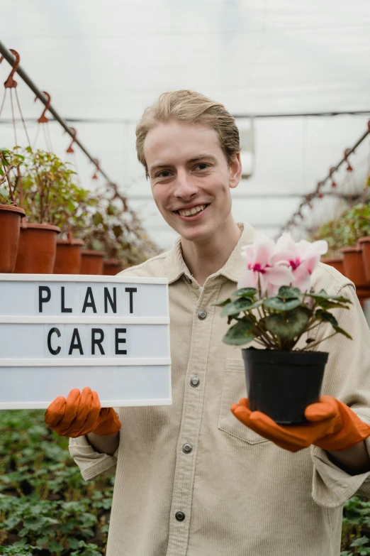 a man holding a sign that says plant care, by Jacob van Utrecht, shutterstock, renaissance, in bloom greenhouse, non-binary, post graduate, a blond