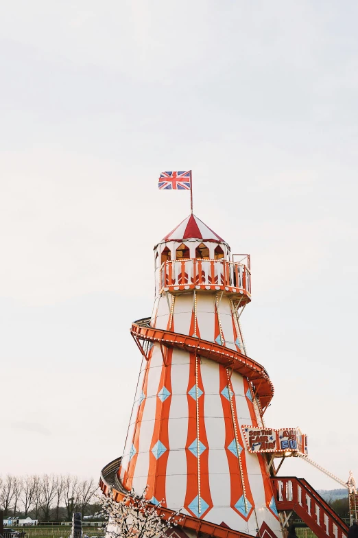 a red and white tower with a flag on top of it, inspired by The Family Circus, unsplash, fairground rides, orange roof, seaside victorian building, 🚿🗝📝