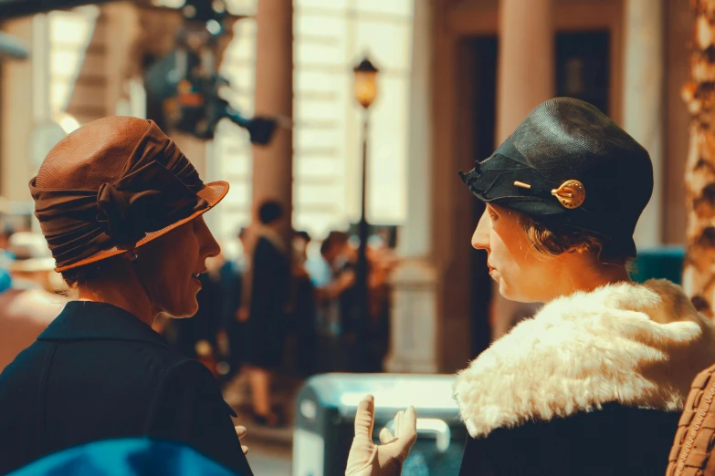 a couple of women standing next to each other, by Emma Andijewska, pexels contest winner, art nouveau, wearing newsboy cap, scene from live action movie, vendors, ( ( theatrical ) )