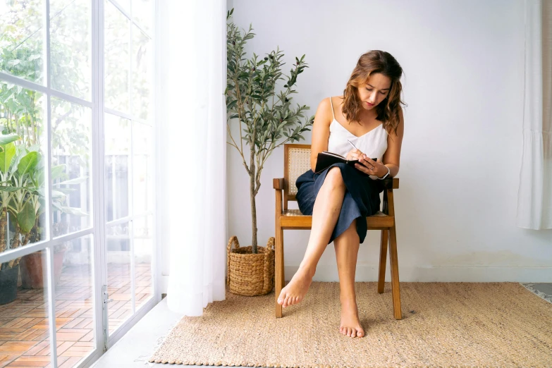 a woman sitting on a chair reading a book, pexels contest winner, photoshoot for skincare brand, bare leg, at home, profile image
