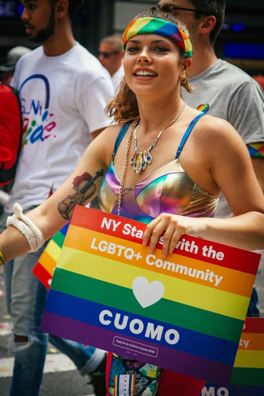 a woman holding a sign that says ny state with the lgbt community, by Julia Pishtar, stuckism, buxom, parade, wearing a tanktop, 🚀🌈🤩