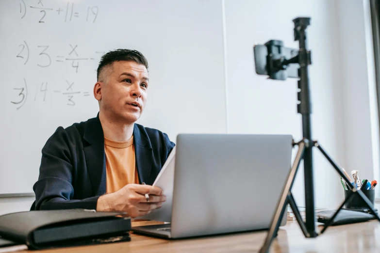 a man sitting in front of a laptop computer, unsplash, academic art, standing in class, webcam, maths, giving an interview