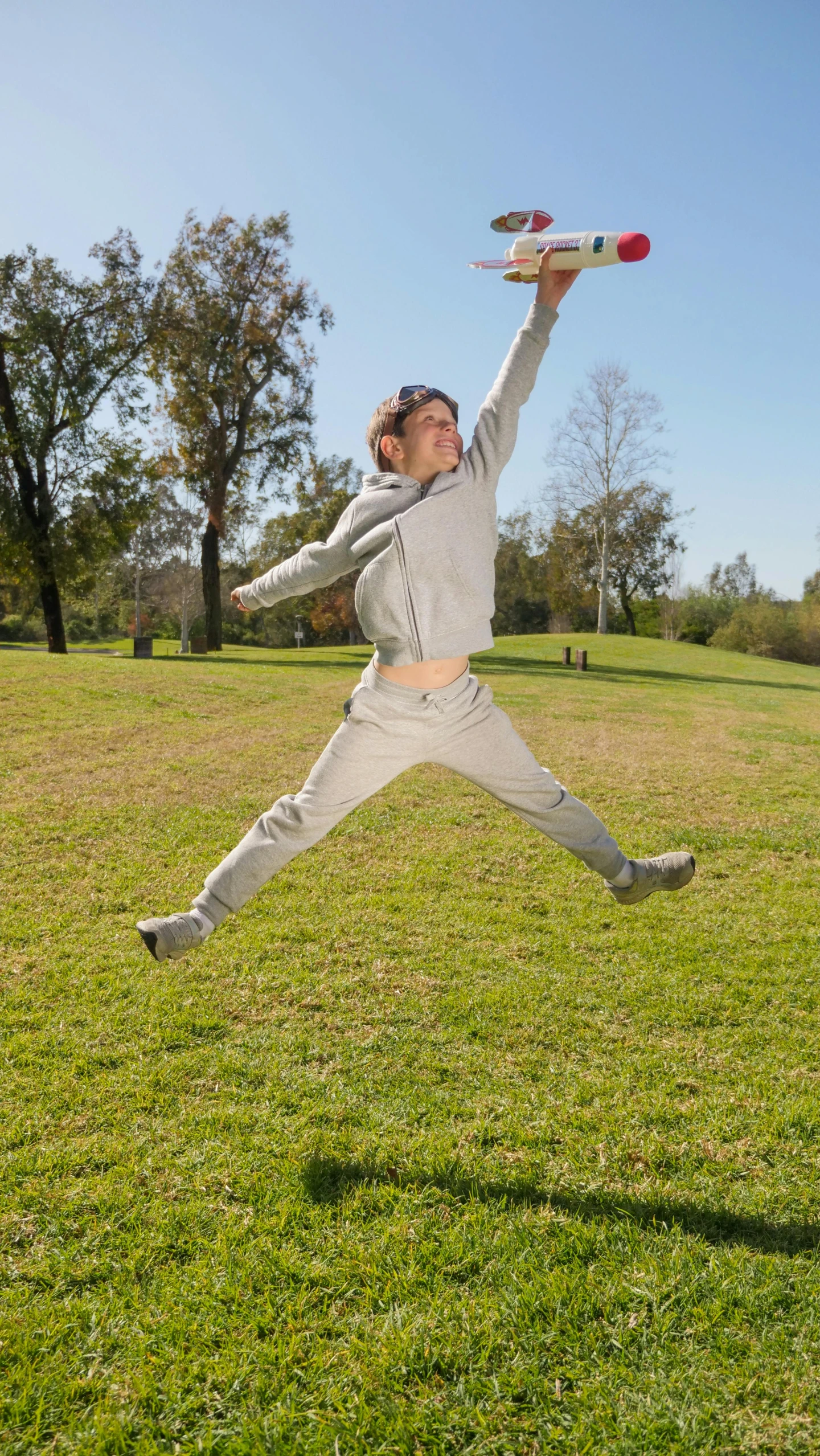 a man jumping in the air to catch a frisbee, an album cover, pexels, happening, wearing a track suit, park, grey, bella poarch