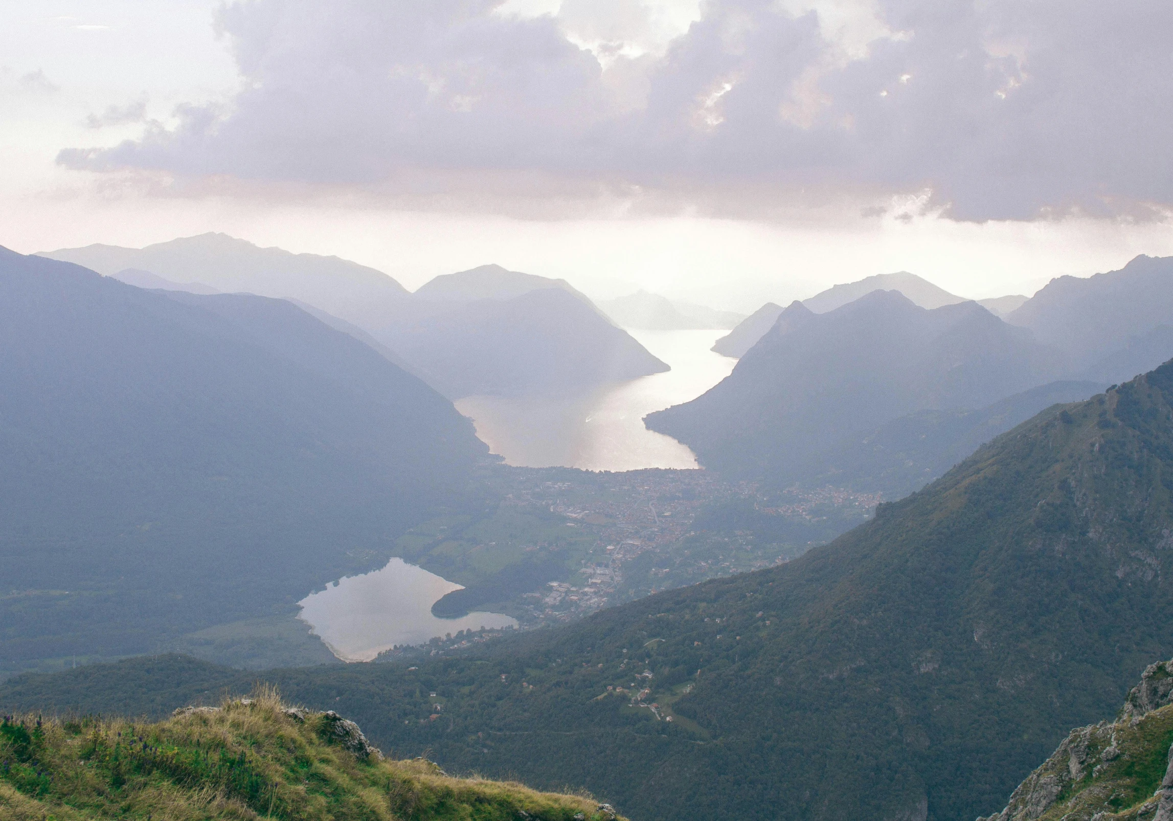 a couple of sheep standing on top of a lush green hillside, pexels contest winner, art nouveau, lakeside mountains, vouge italy, dark-skinned, entire city in view