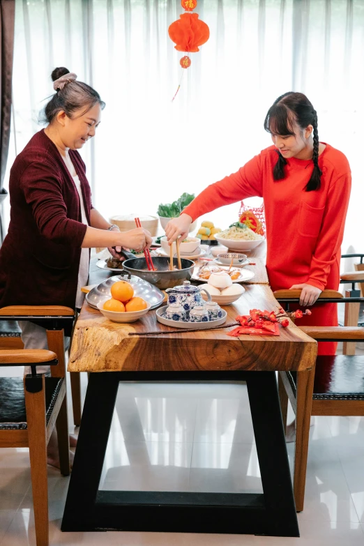 a couple of women standing next to each other at a table, inspired by Cui Bai, pexels contest winner, cooking it up, panoramic shot, seasonal, chinese style