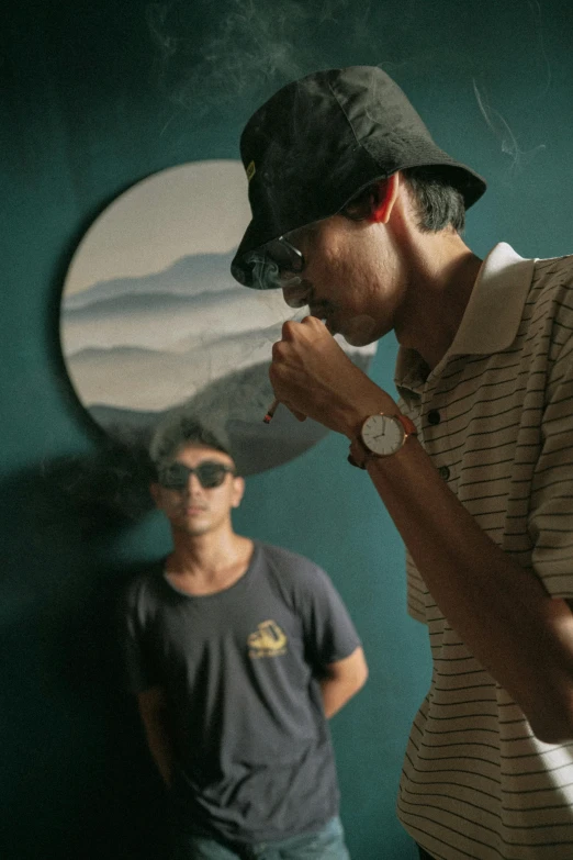 a man smoking a cigarette next to another man, by Basuki Abdullah, unsplash contest winner, visual art, wearing sunglasses and a cap, still from a music video, smoke filled room, tall thin