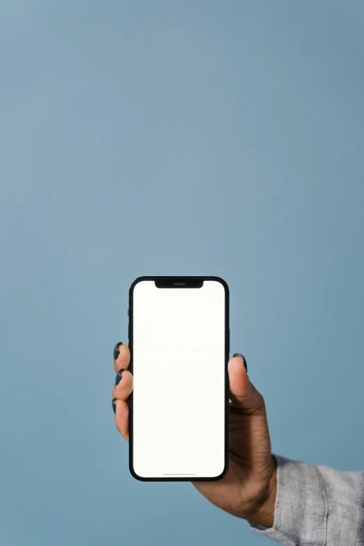 a person holding up an iphone with a white screen, by Carey Morris, trending on pexels, minimalism, solid blue background, dark skin tone, rounded corners, vertical wallpaper