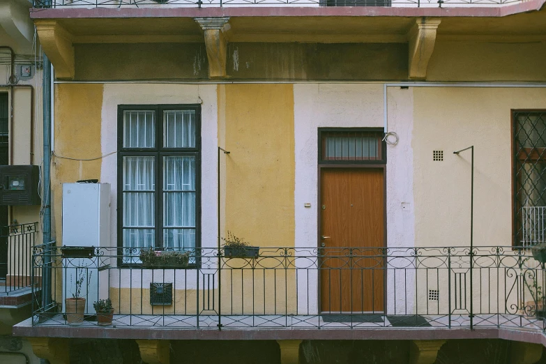 a red fire hydrant sitting on the side of a building, a photo, by Attila Meszlenyi, modernism, balcony door, pale yellow walls, zdzislaw bekinski, terraced