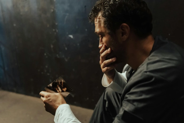 a man sitting on the ground smoking a cigarette, a portrait, by Daniel Lieske, pexels contest winner, hyperrealism, sad prisoner holding ipad, ( ( theatrical ) ), holding a wood piece, robert sheehan