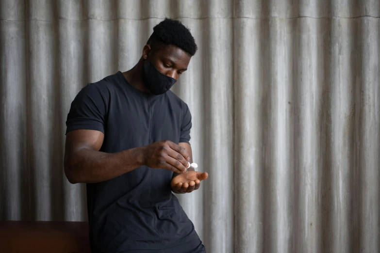 a man in a black shirt is putting something in his hand, pexels contest winner, jaylen brown, white man with black fabric mask, steroid use, wearing fitness gear