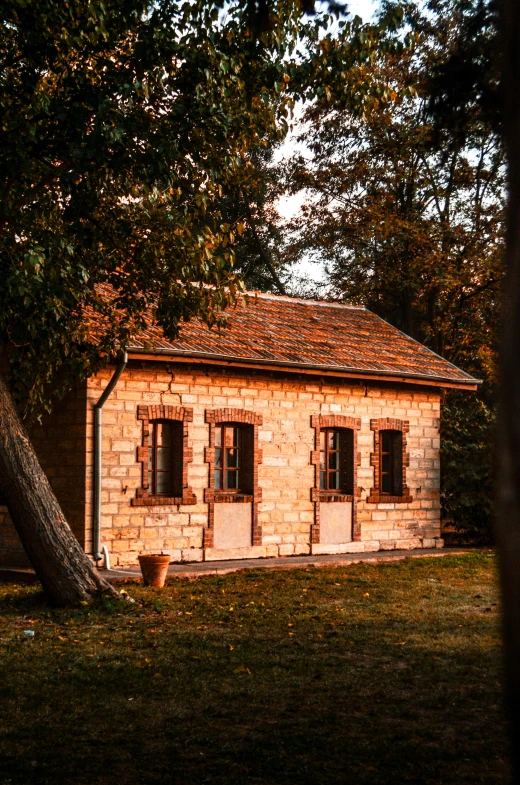 a small building sitting on top of a lush green field, inspired by Henri Harpignies, pexels contest winner, autumn sunrise warm light, built into trees and stone, an escape room in a small, a quaint