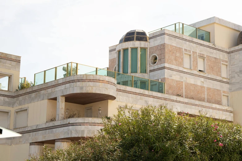 a tall building sitting next to a lush green tree, inspired by Ricardo Bofill, unsplash, art nouveau, jerusalem, on a rooftop, beachfront mansion, conde nast traveler photo