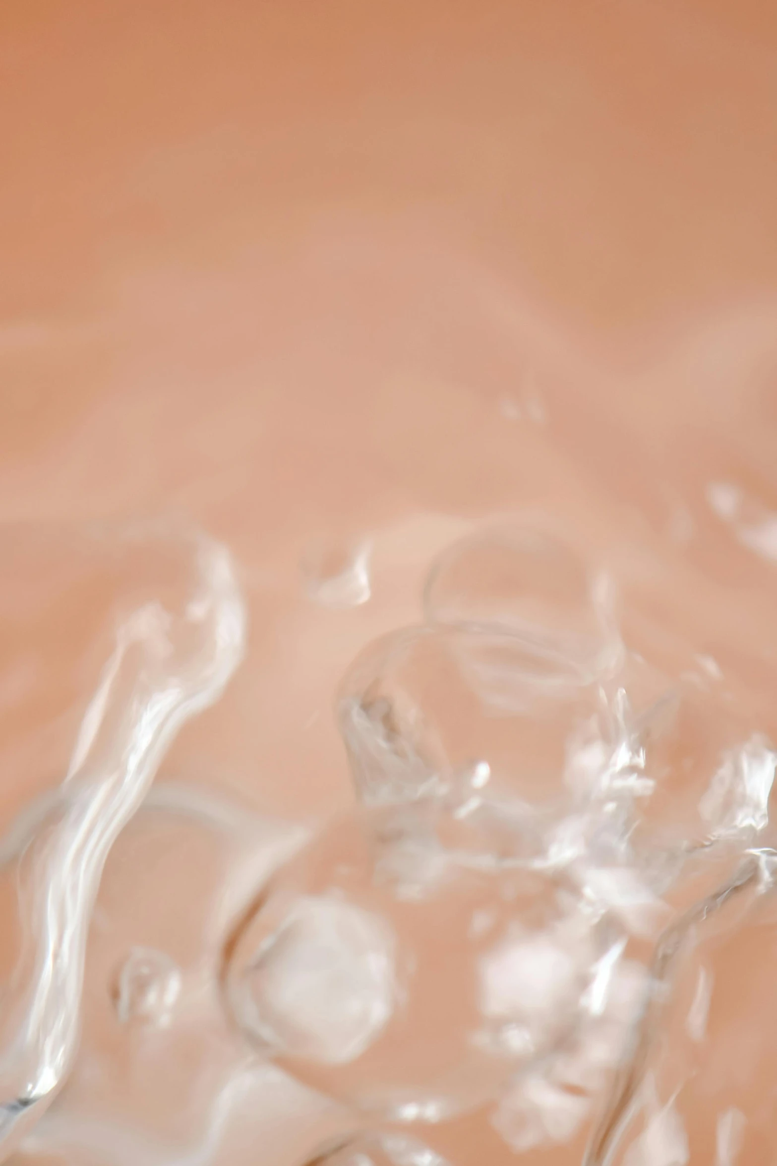 a close up of a toothbrush on a table, flowing salmon-colored silk, face in water, crystalline skin, shot from below