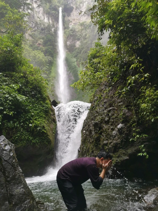 a man taking a picture of a waterfall, doing a prayer, lascivious pose, coban, leaked photo