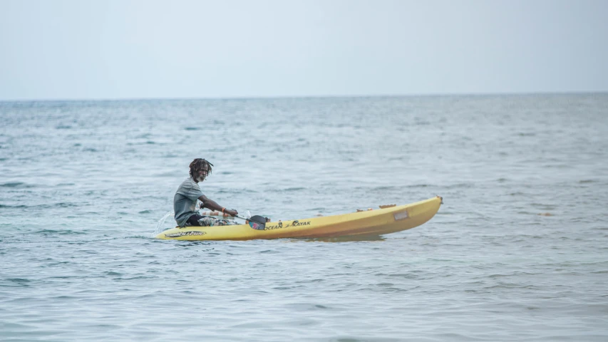 a man sitting on top of a yellow surfboard in the ocean, hurufiyya, adut akech, photograph taken in 2 0 2 0, small canoes, thumbnail