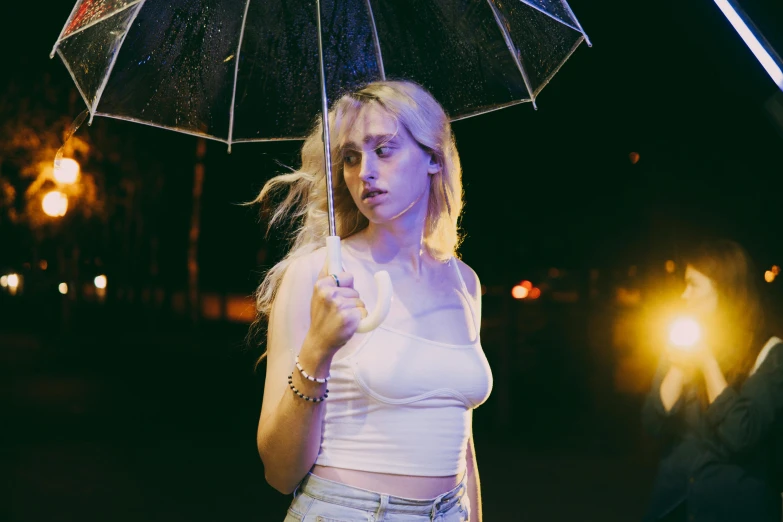 a woman holding an umbrella in the dark, an album cover, inspired by Elsa Bleda, unsplash contest winner, realism, portrait of kim petras, natalia dyer, wearing a camisole, wet street