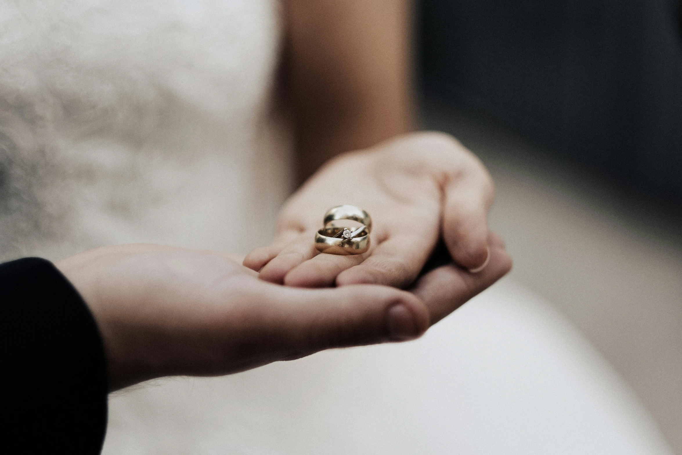 a close up of a person holding a wedding ring, by Nina Hamnett, unsplash, white and gold, varying thickness, a small, then another