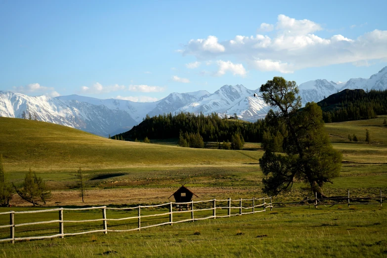 a fenced in field with mountains in the background, pexels contest winner, hurufiyya, mongol, conde nast traveler photo, a cozy, grazing