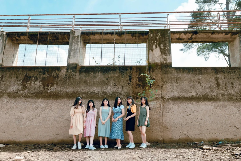 a group of women standing in front of a wall, an album cover, inspired by Kim Jeong-hui, unsplash, standing in abandoned building, group of seven, ulzzang, wearing dresses