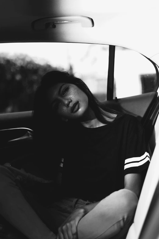 a woman sitting in the back seat of a car, a black and white photo, inspired by Elsa Bleda, tumblr, soft devil queen madison beer, with closed eyes, lowres, icon black and white