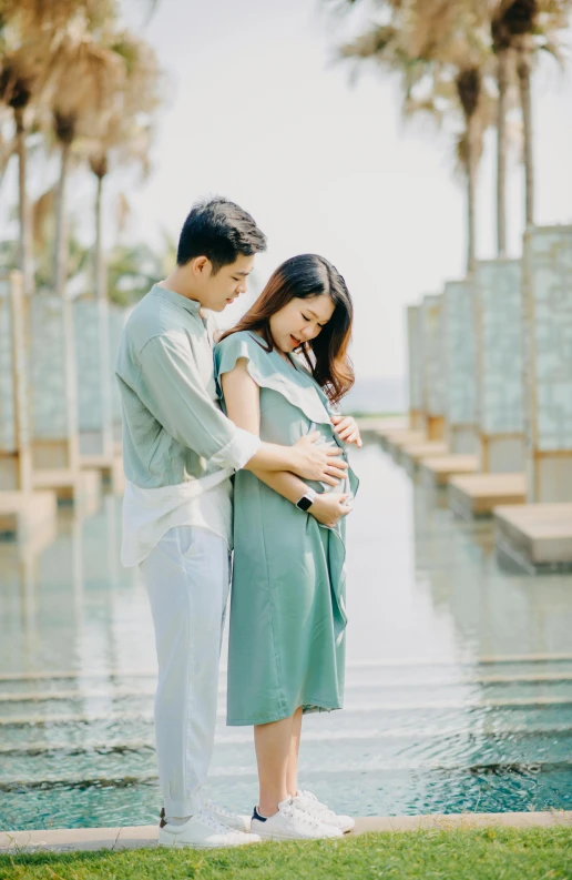 a man and woman standing next to each other near a pool, a picture, by Basuki Abdullah, unsplash, happening, pregnant belly, sea - green and white clothes, korean, icon
