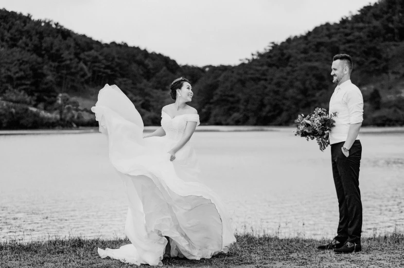 a black and white photo of a bride and groom, by Nándor Katona, unsplash, wearing a dress made of water, hyung-tae kim, on a lake, flowy