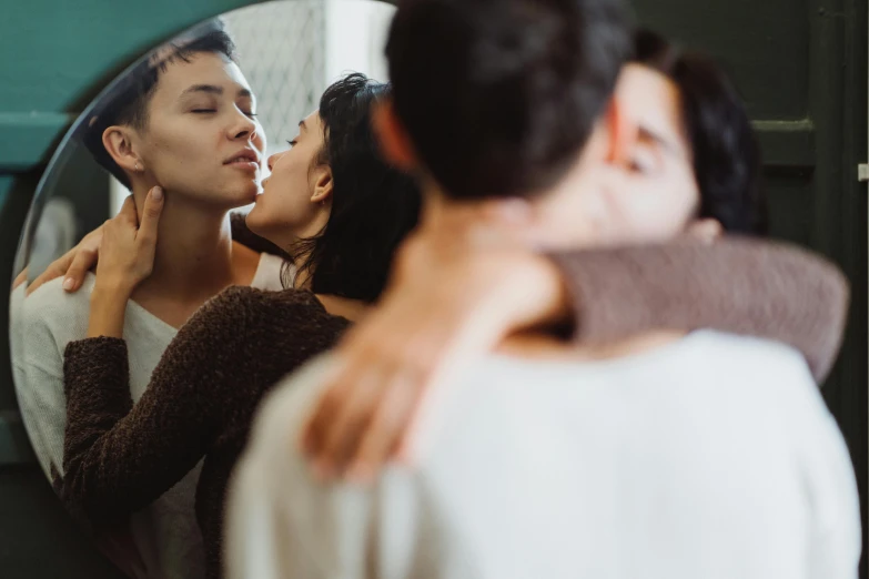 a man kissing a woman in front of a mirror, a photo, trending on pexels, alessio albi and shin jeongho, woman holding another woman, family friendly, tight around neck