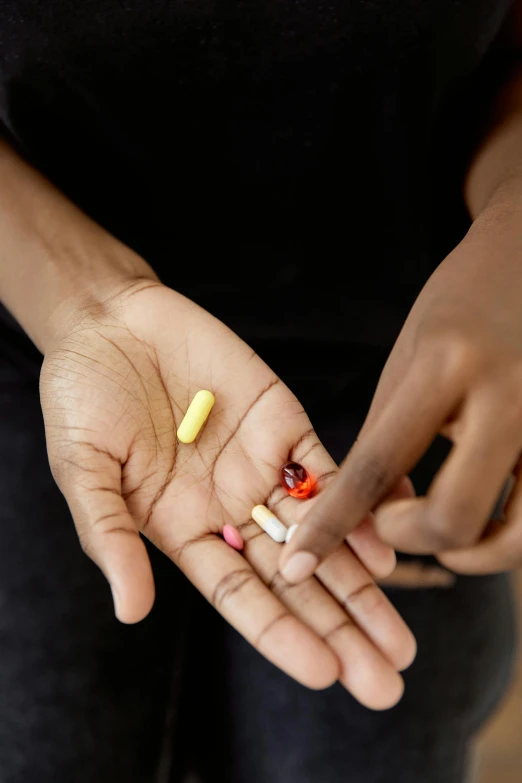 a woman holding a handful of pills in her hands, by Jessie Algie, antipodeans, photo of a black woman, 15081959 21121991 01012000 4k, multi - coloured, journalism photo