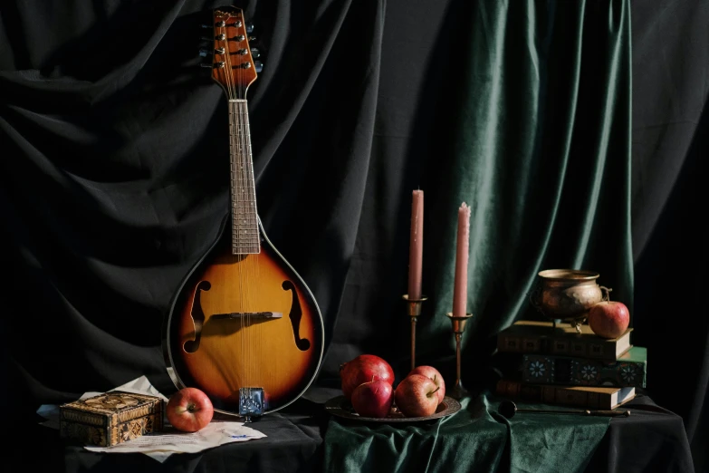 a guitar sitting on top of a table next to a pile of books, an album cover, inspired by Orazio Gentileschi, unsplash contest winner, baroque, playing a mandolin, still life of an apple, on a velvet tablecloth, studio shoot