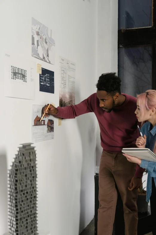 a couple of people that are standing in front of a wall, trending on unsplash, academic art, architect studio, teaching, display”, in a gallery setting