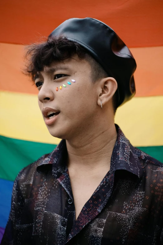 a man standing in front of a rainbow flag, trending on unsplash, sumatraism, portrait androgynous girl, boyish face, indonesia, pouting