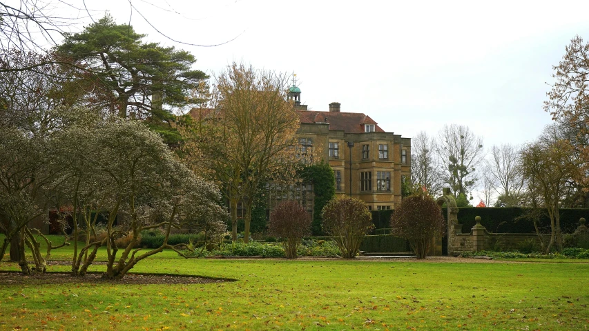 a large house sitting on top of a lush green field, inspired by Mary Adshead, pixabay, barbizon school, exterior botanical garden, verdigris, autumnal colours, overcast