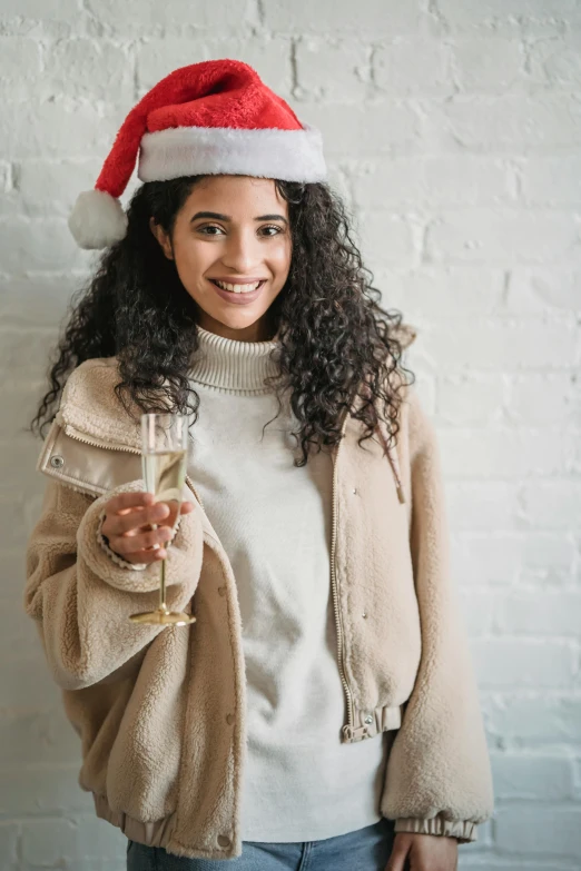 a woman in a santa hat holding a glass of wine, a portrait, pexels, wearing off - white style, curly, 1 0, college