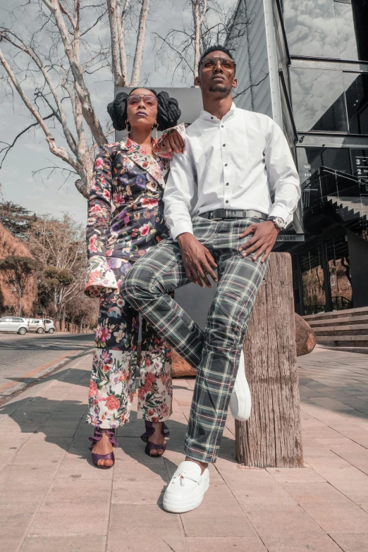 a man and a woman sitting on a tree stump, by Ingrida Kadaka, trending on unsplash, wearing an ornate suit, standing in township street, modelling, promotional image