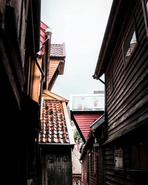 a couple of buildings that are next to each other, by Christen Dalsgaard, pexels contest winner, alley, peaked wooden roofs, gif, red brown and grey color scheme