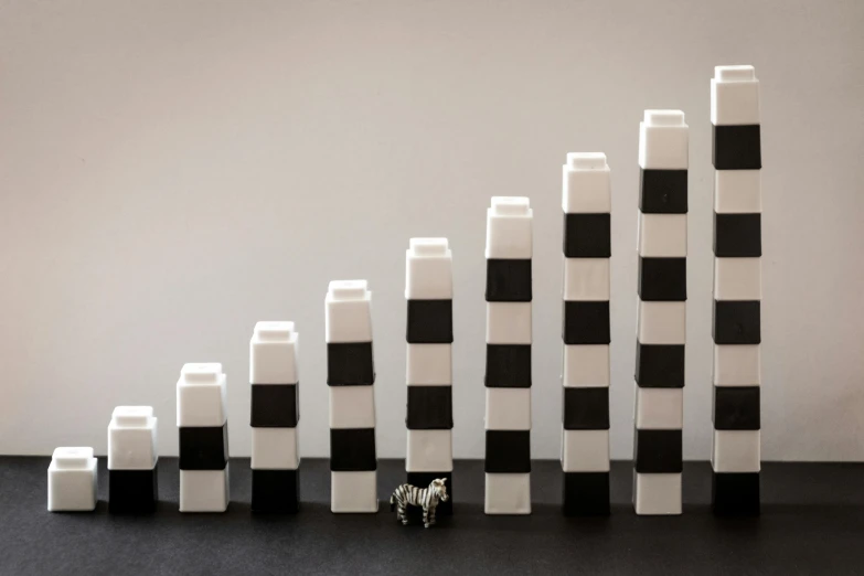 a group of black and white blocks sitting on top of a table, inspired by Frederick Hammersley, unsplash, towering above a small person, beastars legoshi, growth of a couple, minimalist photorealist