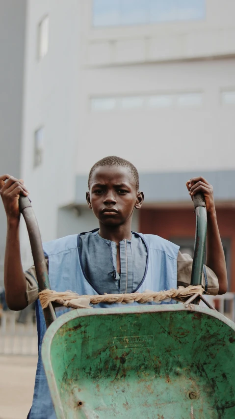 a man pushing a wheelbarrow on a city street, by Attila Meszlenyi, pexels contest winner, light skinned african young girl, close up portrait shot, a cannon mounted on his back, boy with neutral face