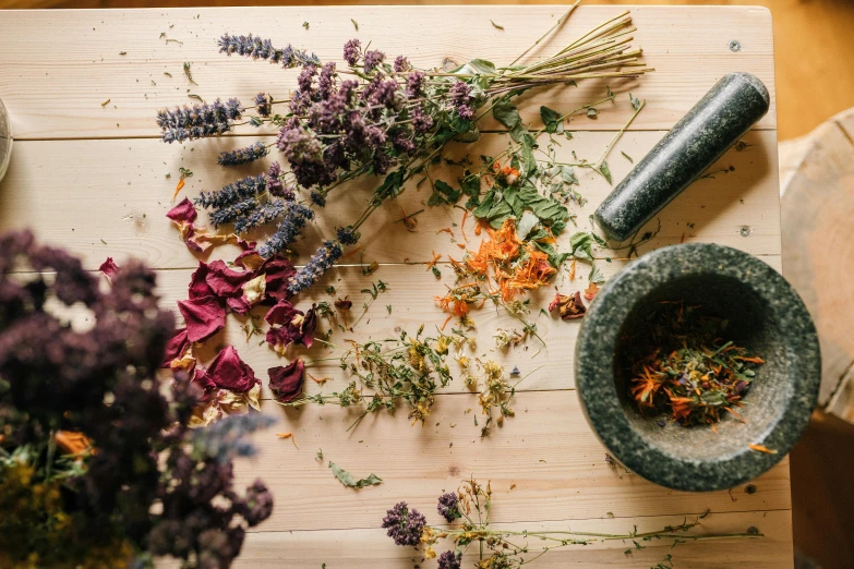 a bunch of flowers sitting on top of a wooden table, by Carey Morris, trending on pexels, dried herbs, mortar and pestle, multicoloured, flattened