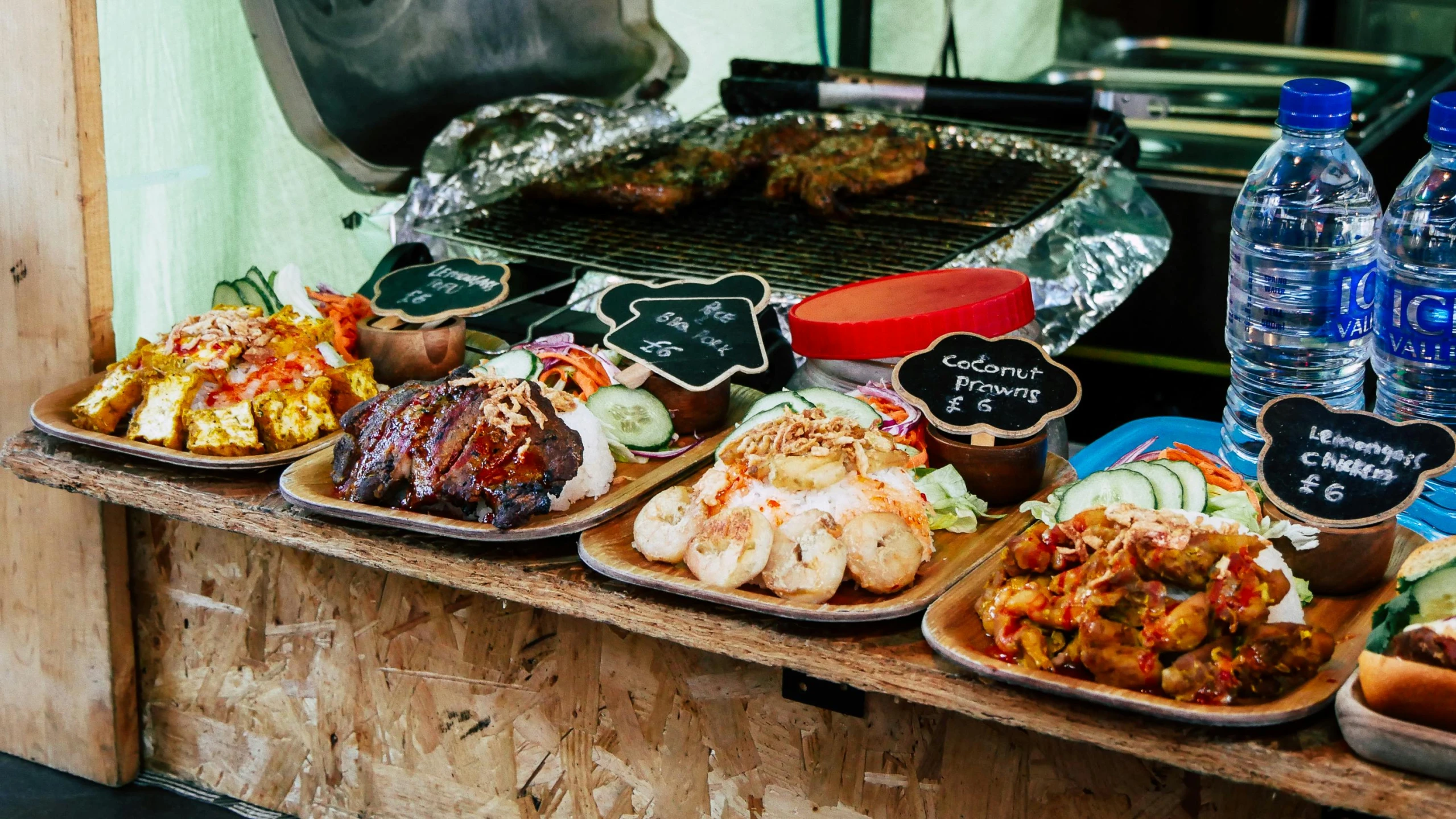 a table topped with plates of food next to bottles of water, unsplash, with street food stalls, smokey burnt envelopes, serving rack of ribs, thumbnail